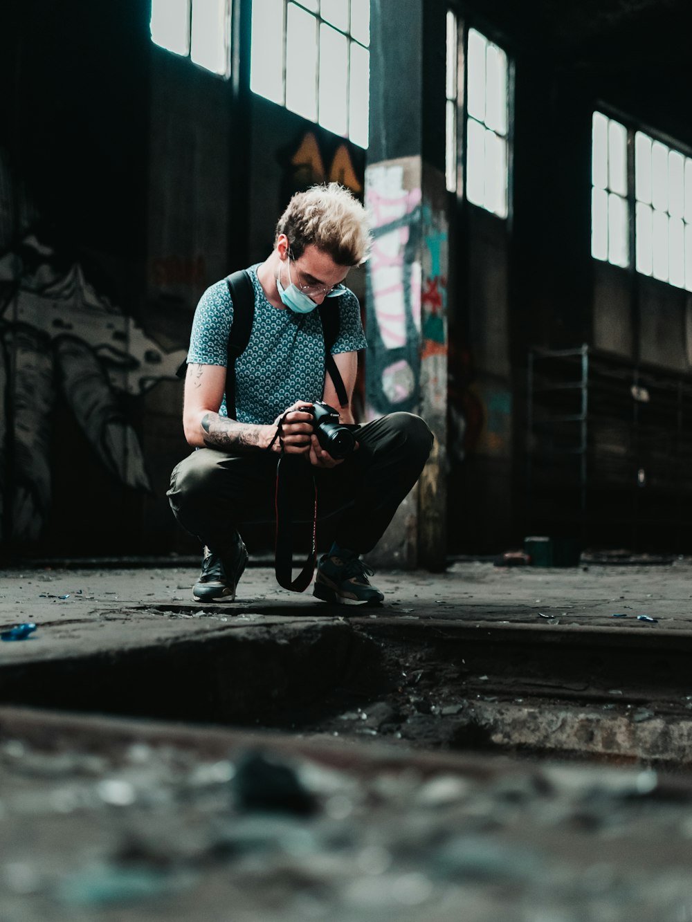 man in blue and white checkered button up shirt and black pants sitting on sidewalk during