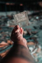 A hand is holding a vintage floppy disk against a blurred background with a bokeh effect. The floppy disk appears worn and aged, suggesting it has been used frequently or stored for a long time.