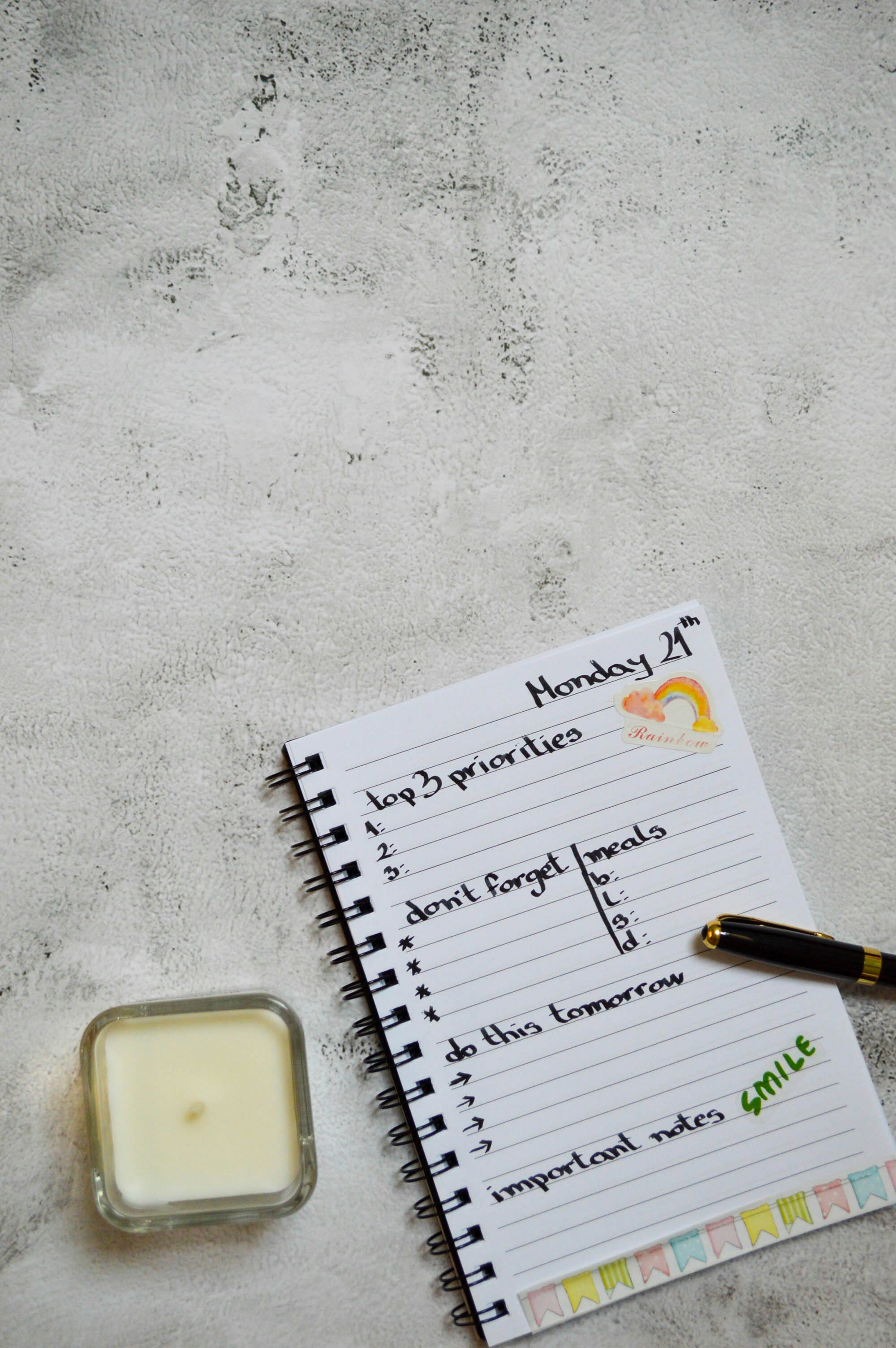 Flatlay of a planner with a pen and candle