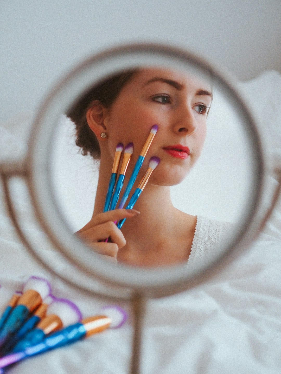 woman in white tank top holding round mirror