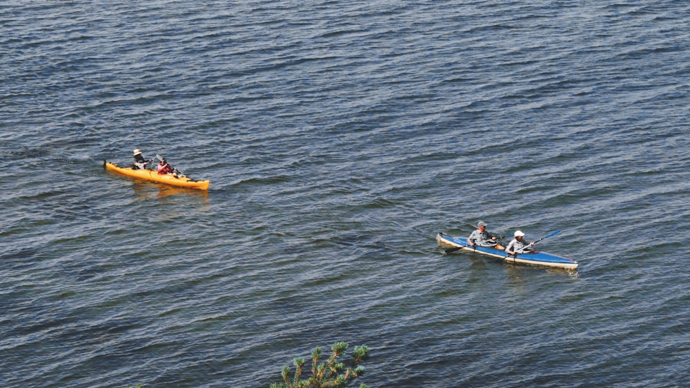 2 people riding on yellow and white kayak on body of water during daytime