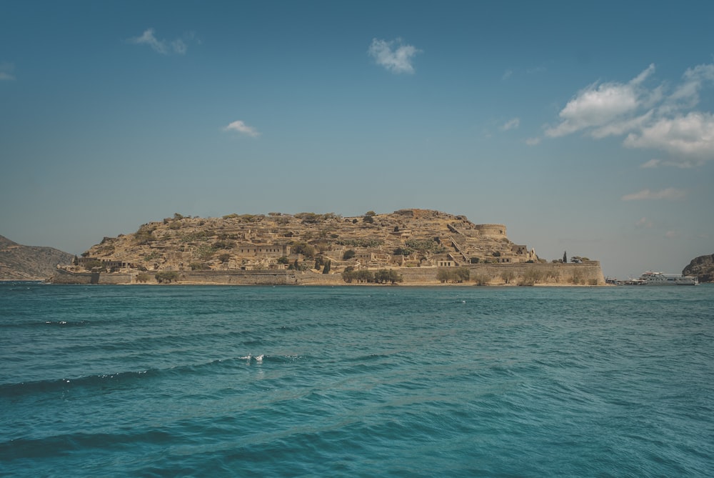 brown rock formation on sea under blue sky during daytime