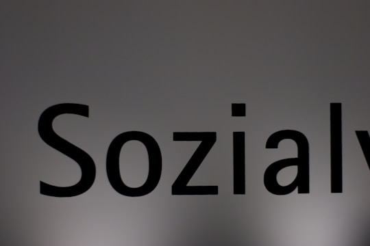 The image features a close-up of the word 'Sozialy' printed in bold black letters on a plain, light gray background. The lighting creates a subtle gradient effect on the background.