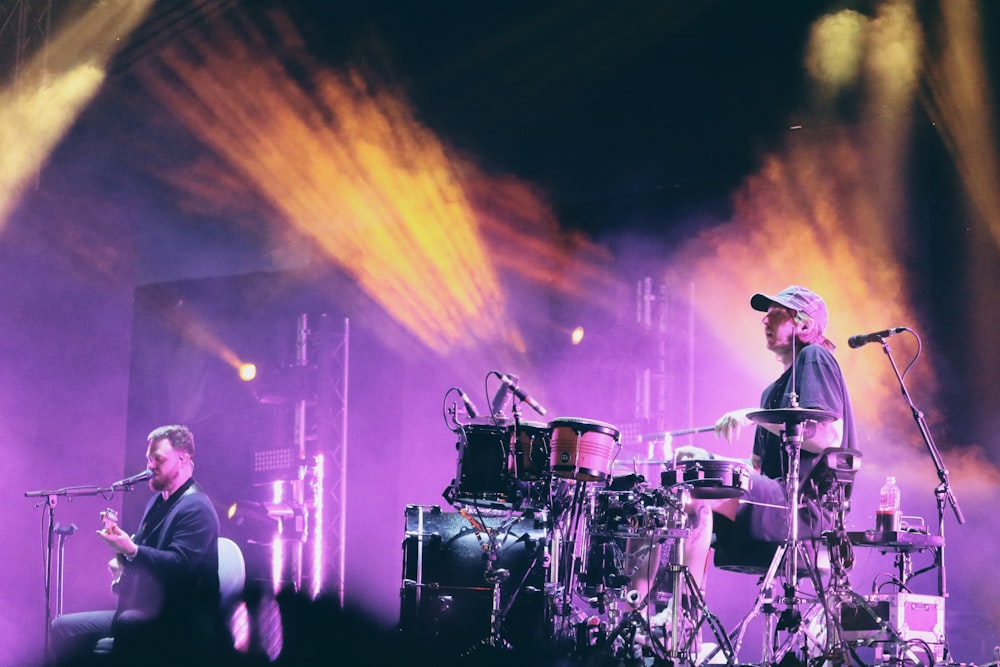 man in white shirt playing drum set