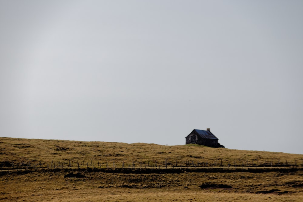 casa de madeira marrom no campo marrom sob o céu branco durante o dia