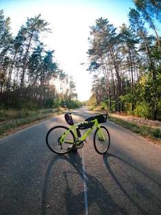 black bicycle on road between trees during daytime