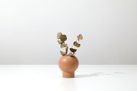 A modern minimalist floral arrangement with mint and eucalyptus green tones on a wooden table