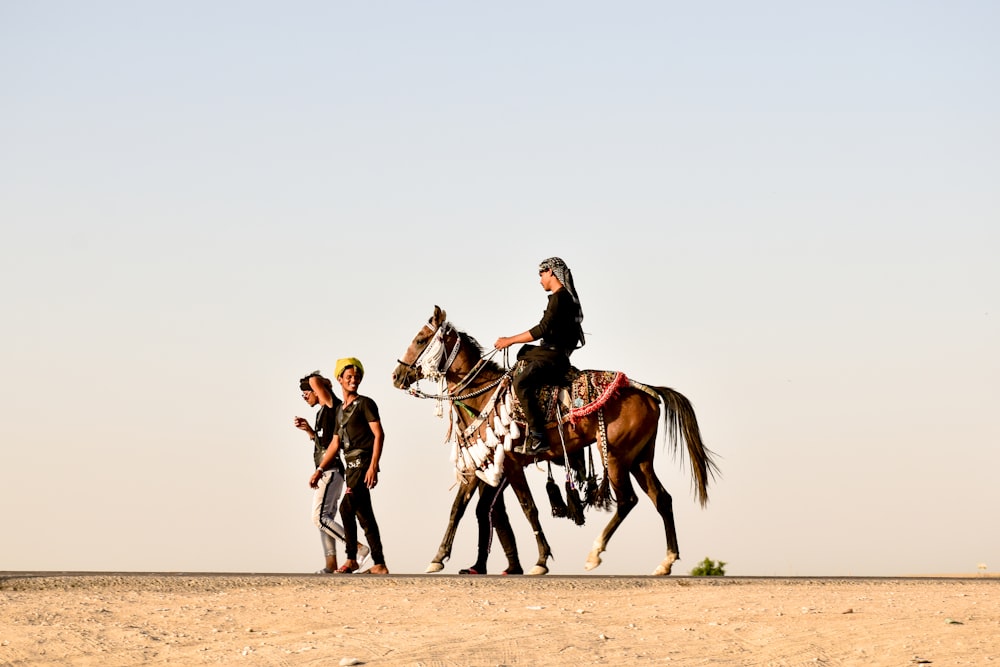 people riding horses on brown sand during daytime