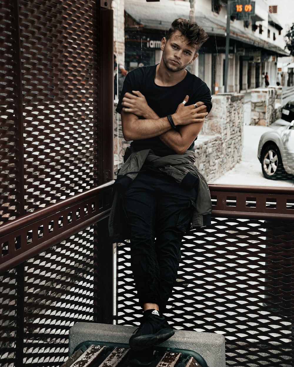 man in black crew neck t-shirt and black pants sitting on brown wooden bench