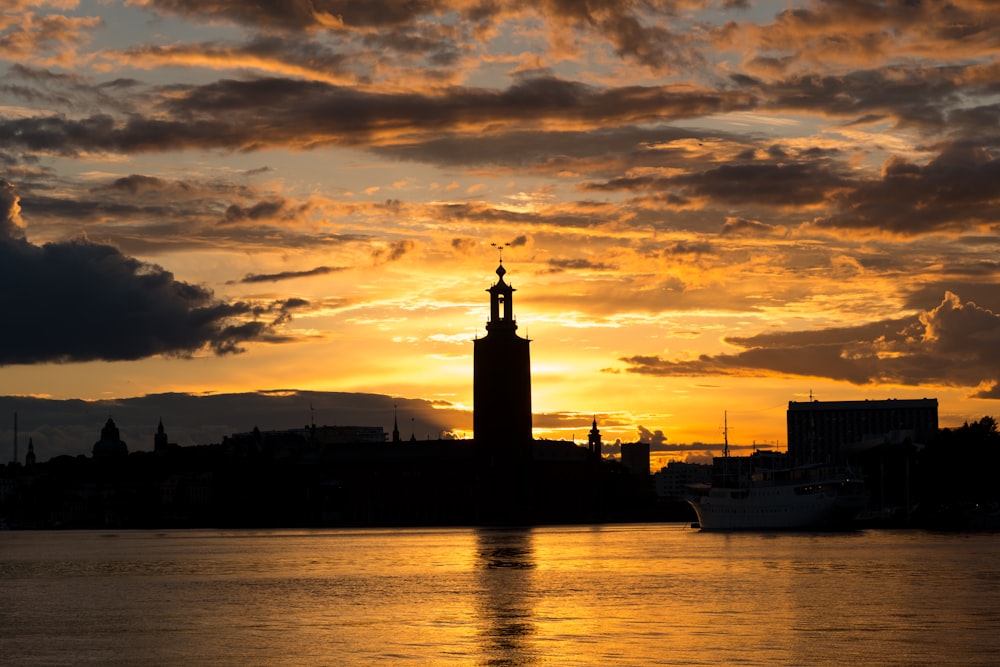 silhouette of building near body of water during sunset