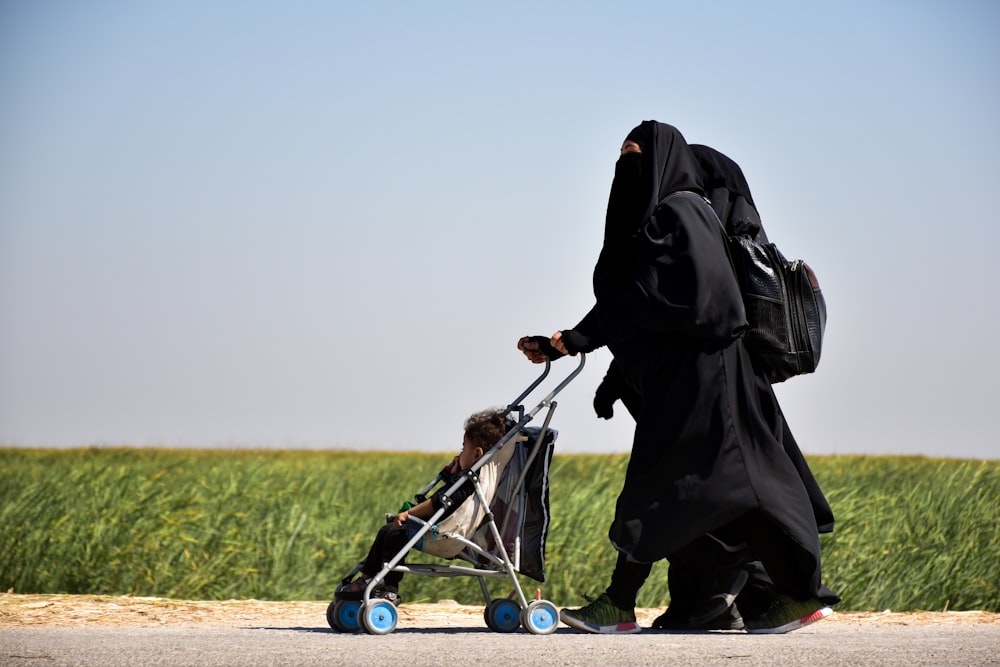 person in black robe holding white and blue kick scooter