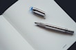 Elegant silver ballpoint pen beside an open planner with handwritten notes