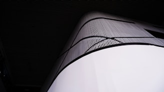 A modern architectural structure featuring smooth, curved surfaces with a vertical pattern of lines and a sleek, minimalist design.