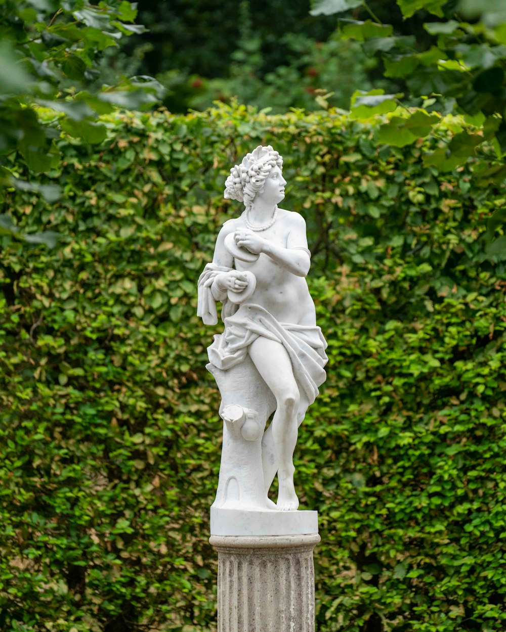 woman statue near green plants during daytime