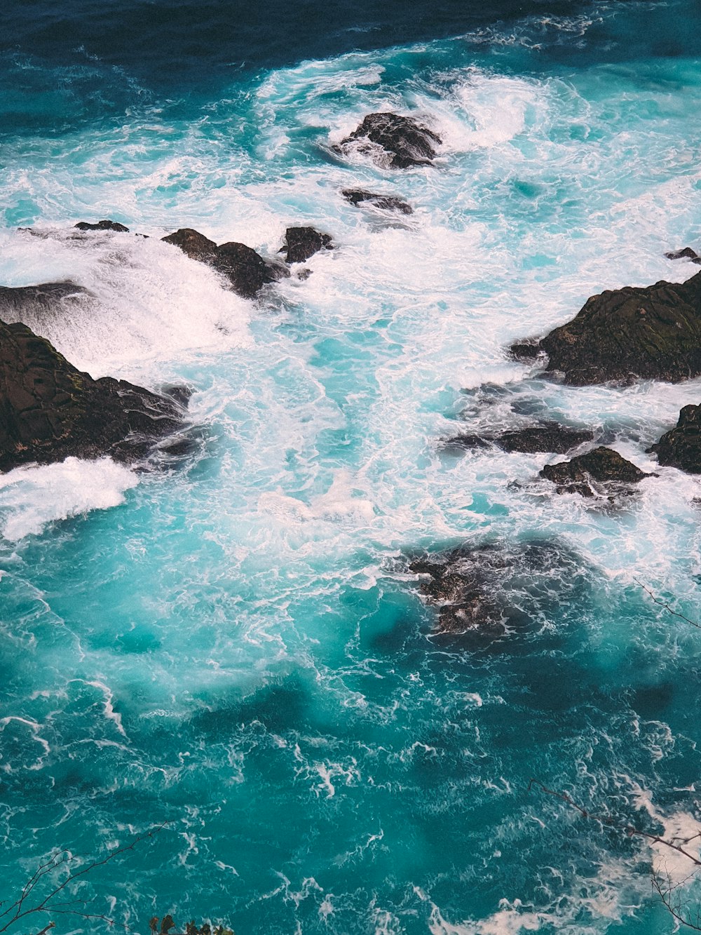 blue ocean waves on black rock formation during daytime