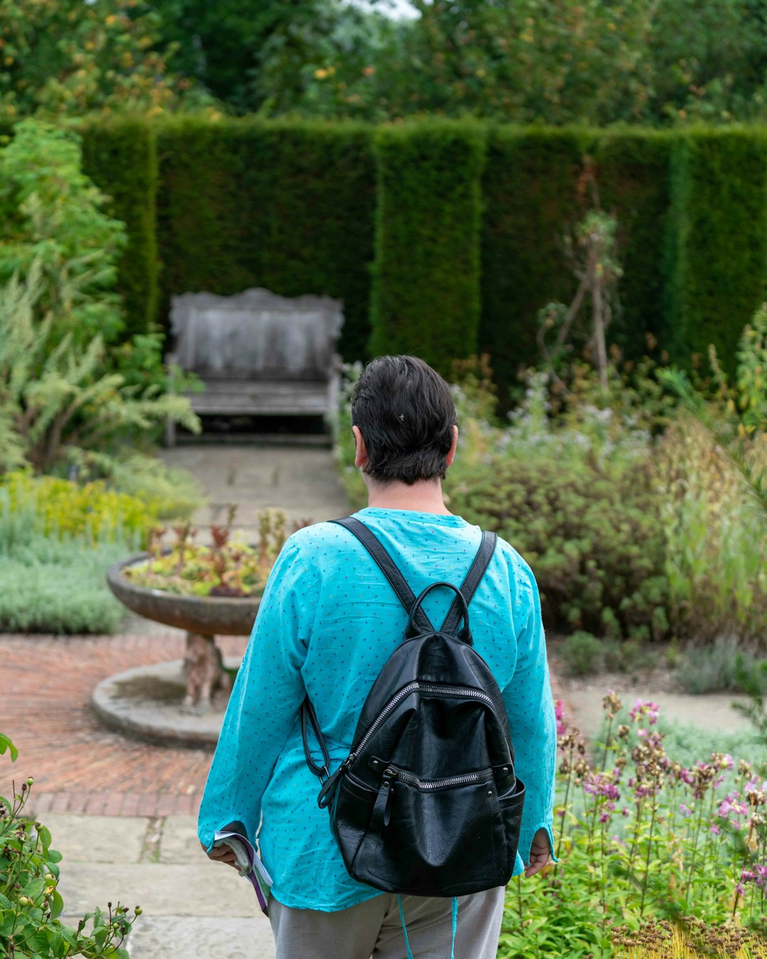 man in blue shirt with black backpack walking on pathway