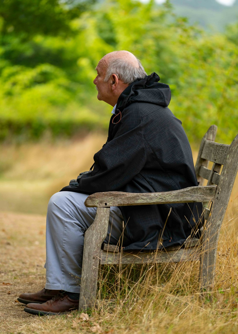 man in black hoodie sitting on brown wooden bench