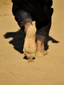 Close-up of shoes walking on a sandy beach, highlighting texture.