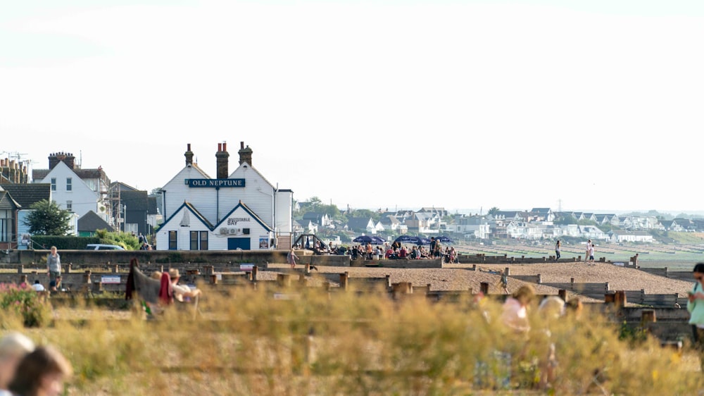 personnes sur un champ d’herbe verte près de la maison blanche et rouge pendant la journée