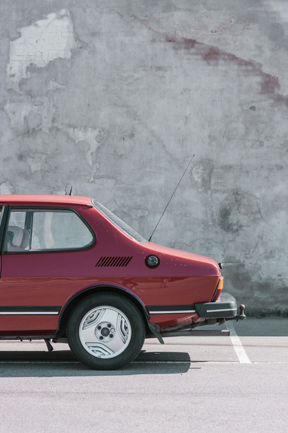 Volkswagen Beetle rojo estacionado junto a una pared gris