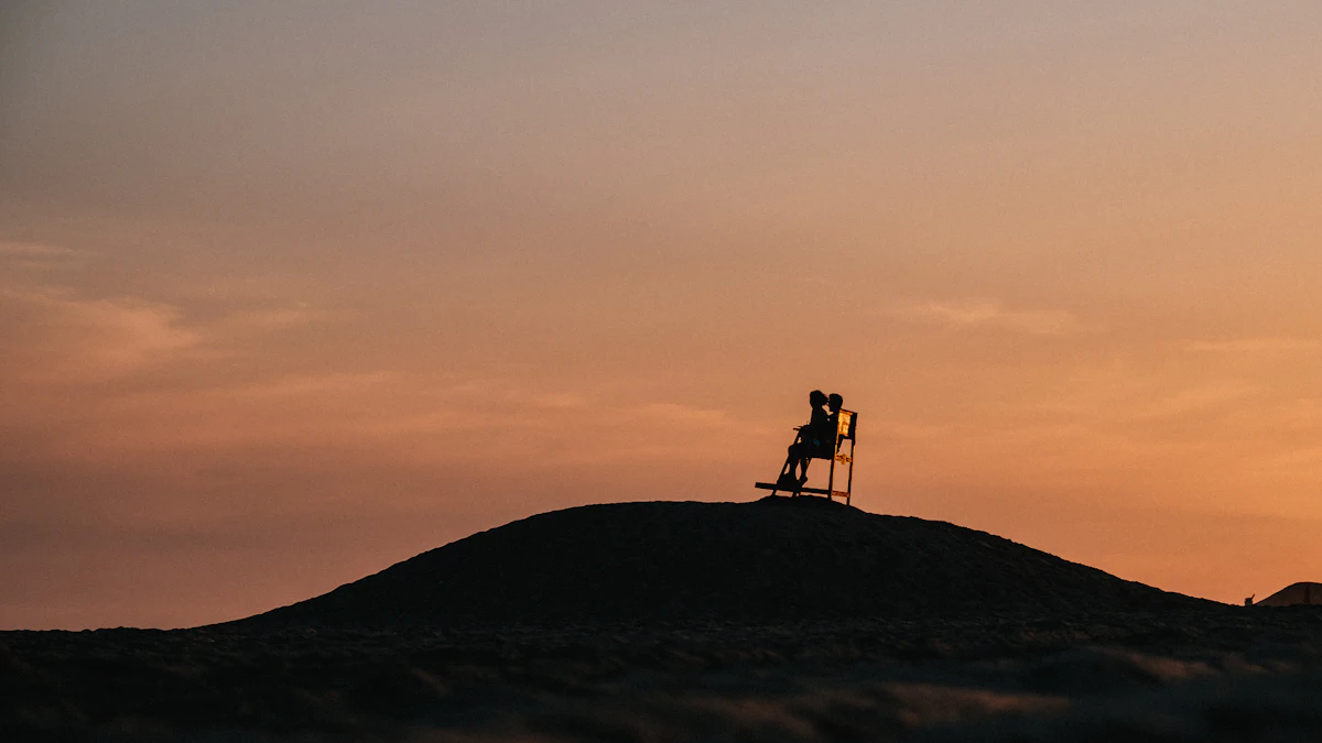 Two silhouettes on a chair on a hilltop at sunset