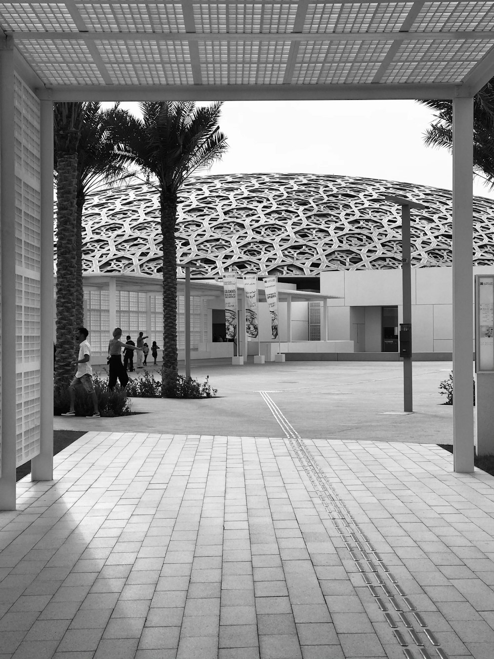 grayscale photo of people sitting on bench near building