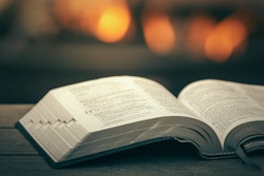 An open book resting on a wooden table with warm light.