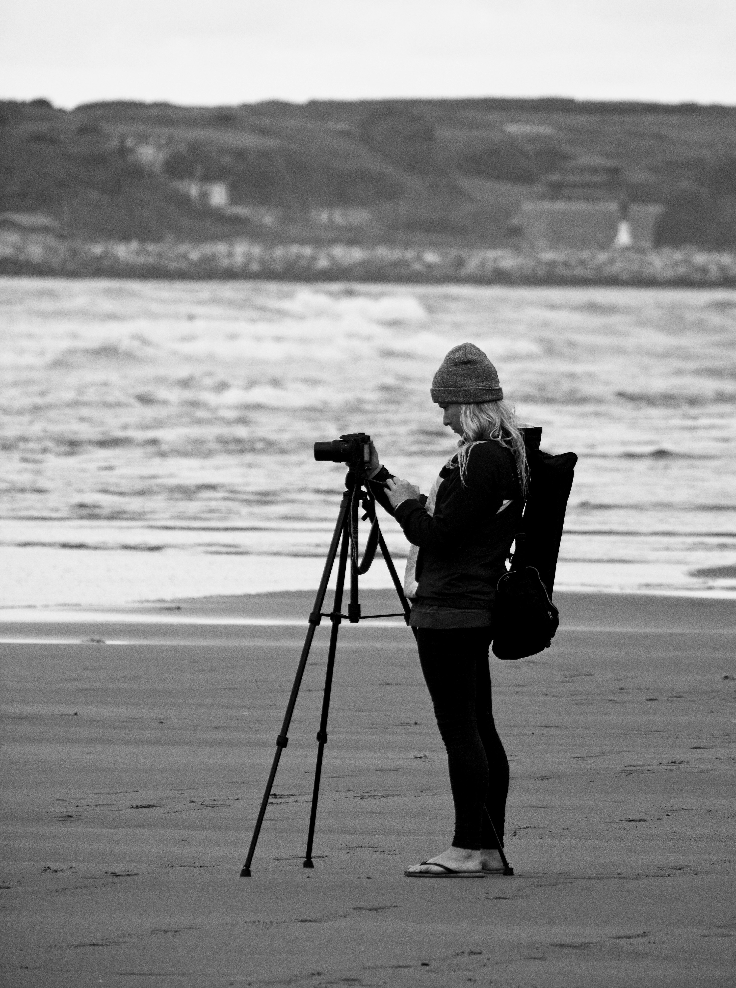 woman in black jacket and pants carrying backpack walking on beach during daytime