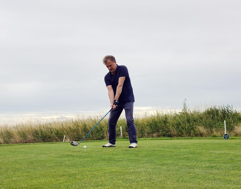 man in black shirt and black pants holding golf club