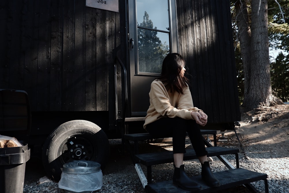 woman in beige long sleeve shirt sitting on brown wooden bench