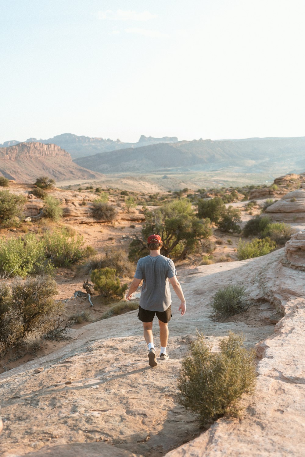 man in gray t-shirt and black shorts walking on dirt road during daytime