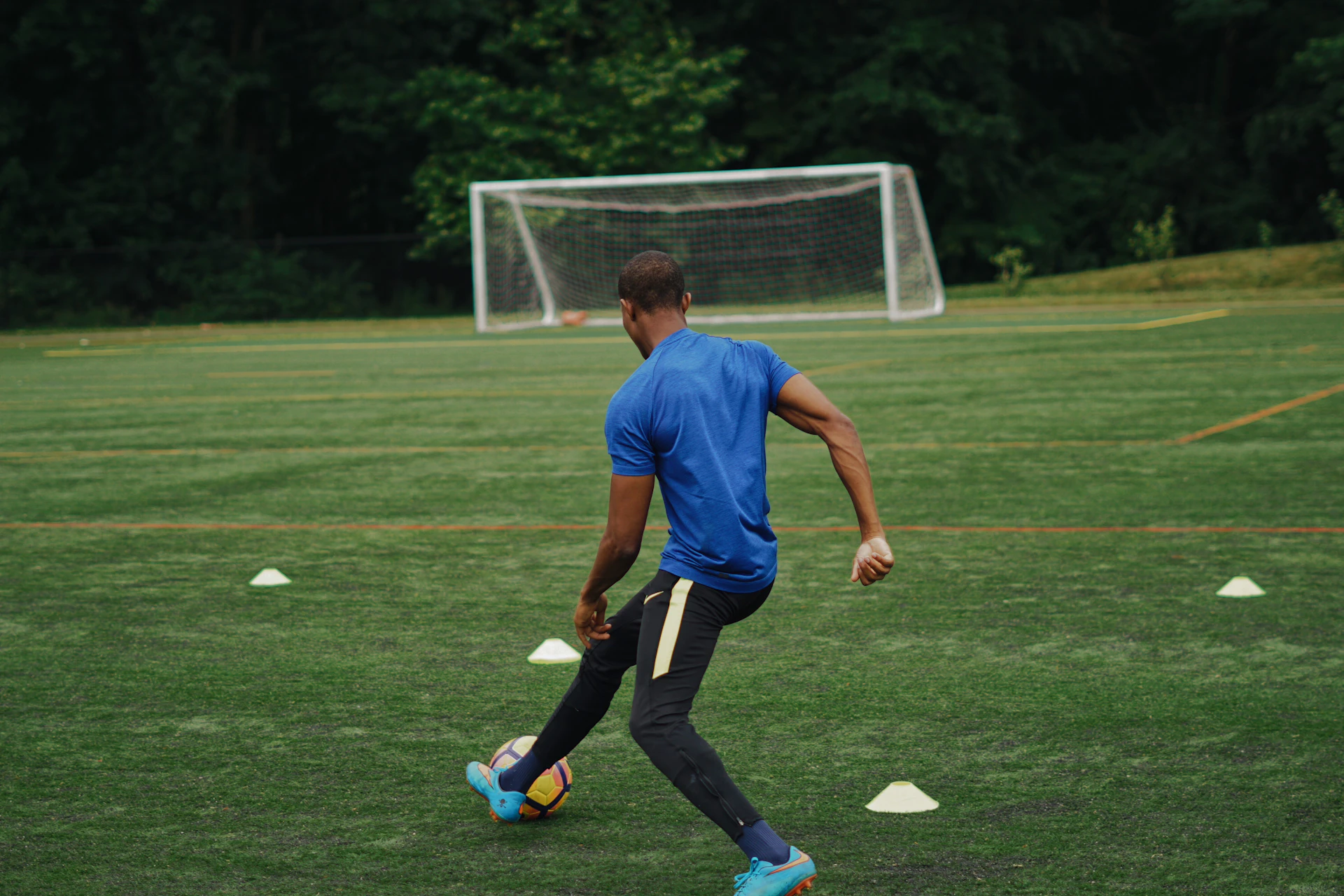 Man in blue shirt playing soccer during daytime.