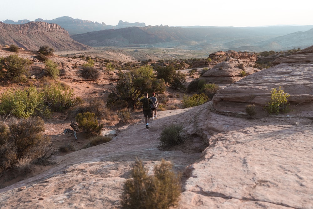 man in black jacket walking on brown rocky mountain during daytime