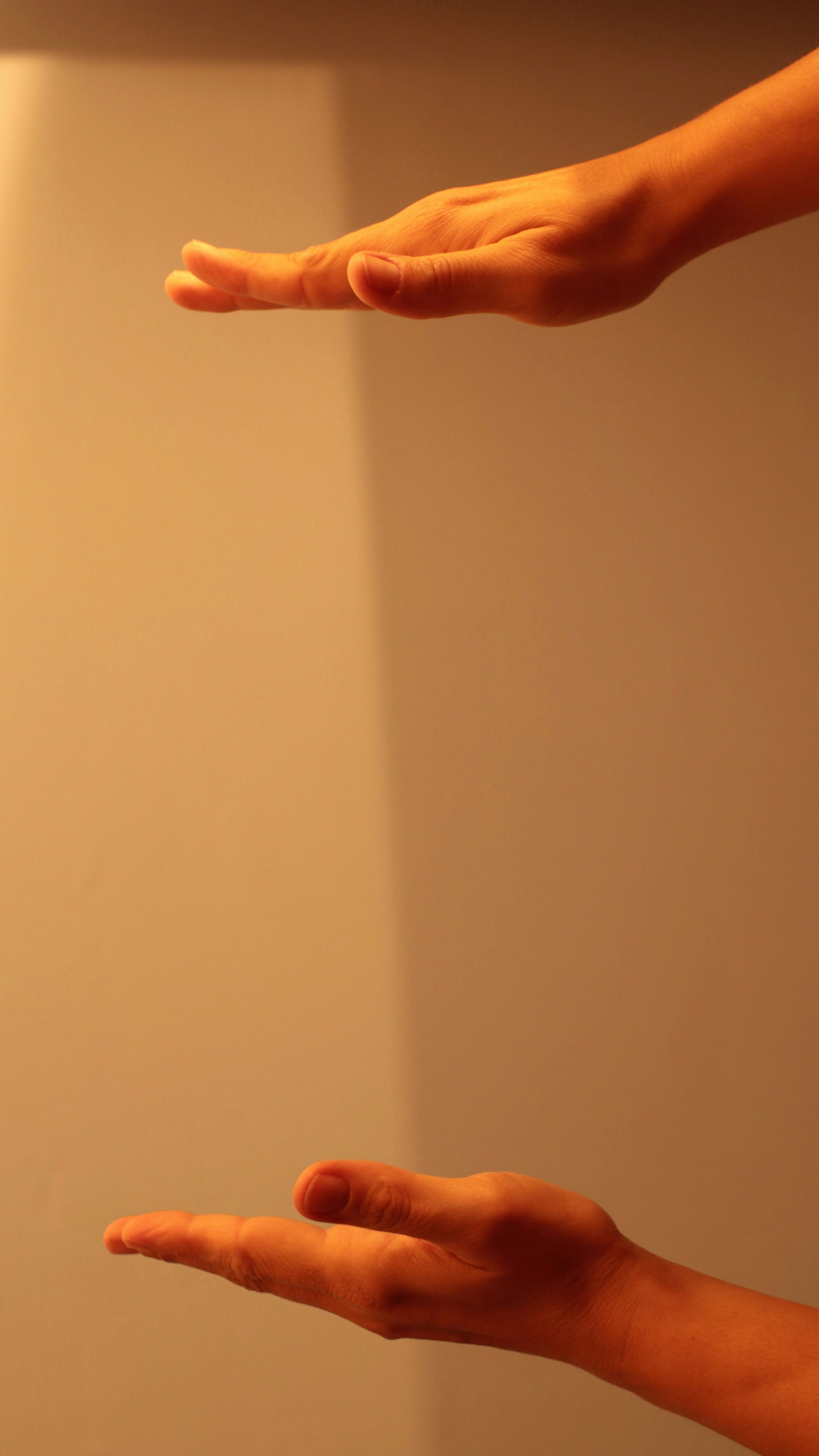 Person extending open hands upward against warm golden light, gesture of offering, spiritual symbolism