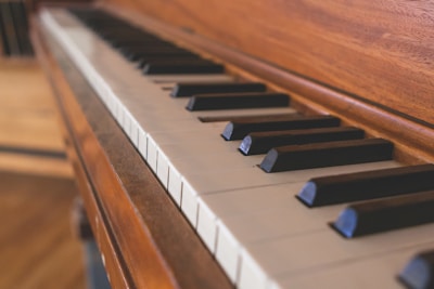 A close-up view of a piano keyboard with a focus on the wooden texture and the arrangement of black and white keys.