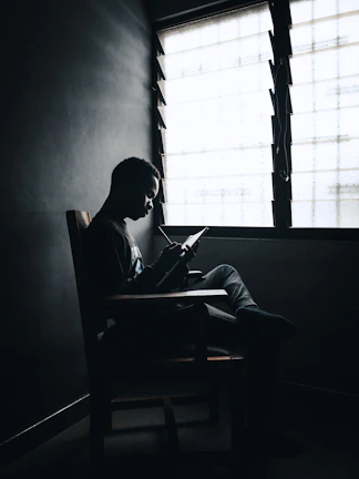 Portrait of the author sitting by a window with a notebook and pen