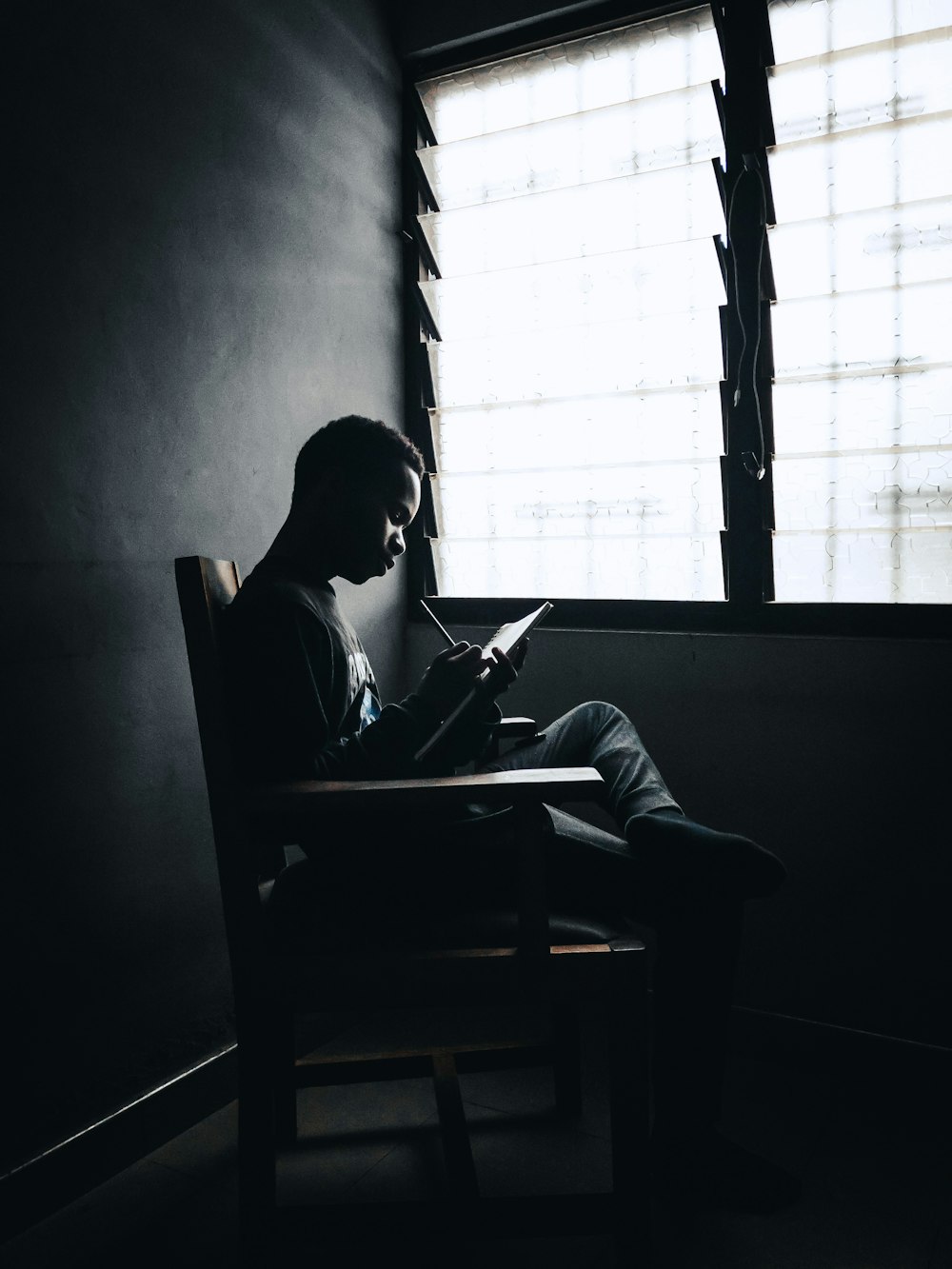 man in black shirt sitting on chair reading book