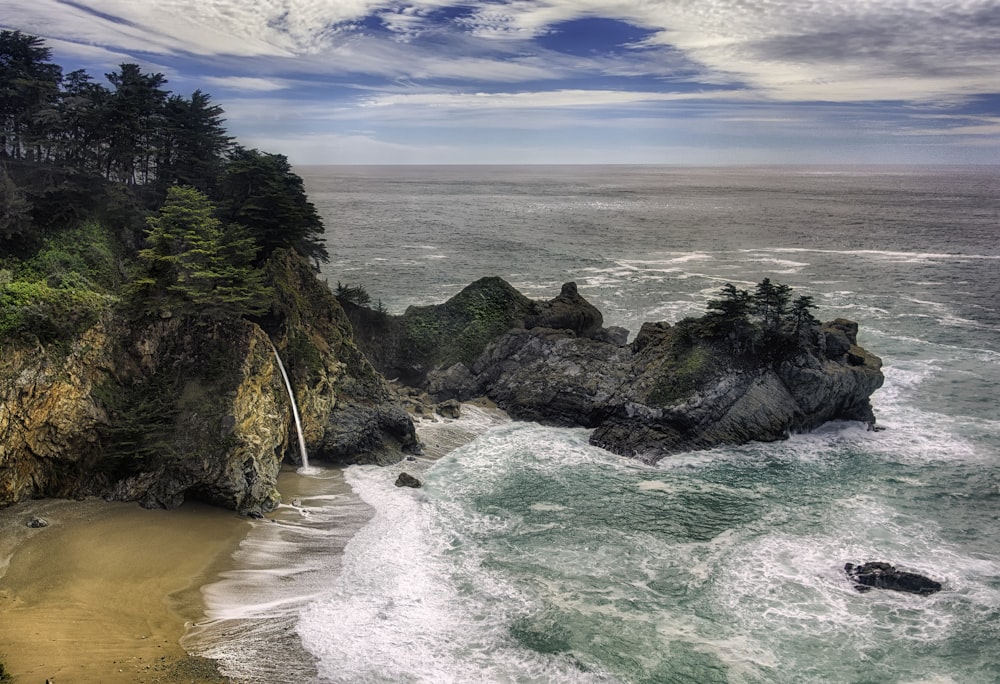 green and brown rock formation on sea shore during daytime