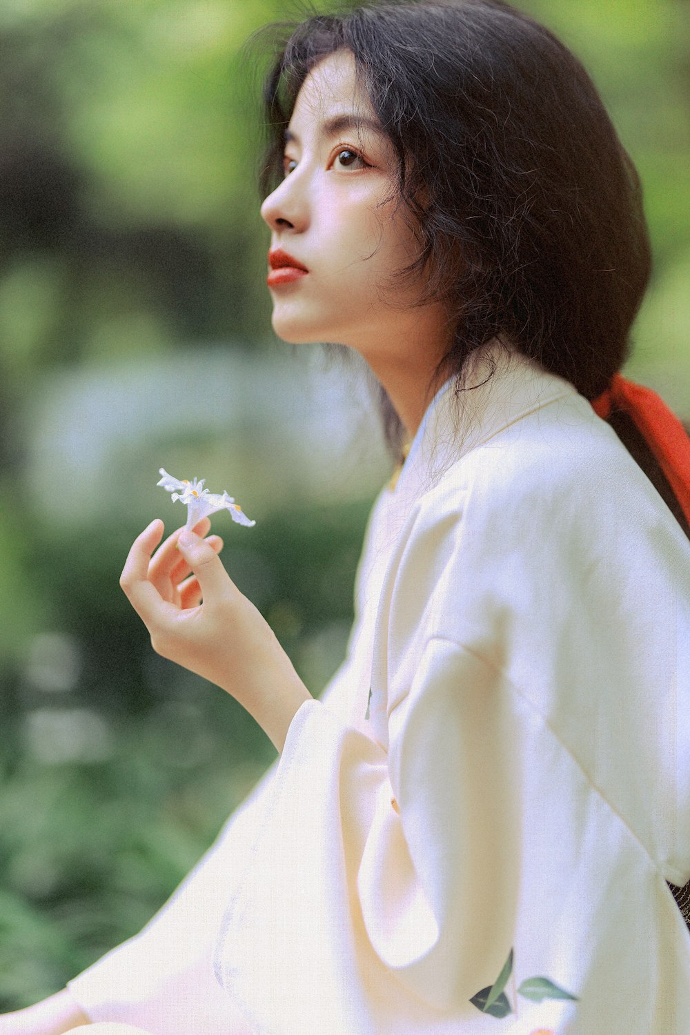 woman in white long sleeve shirt holding white flower