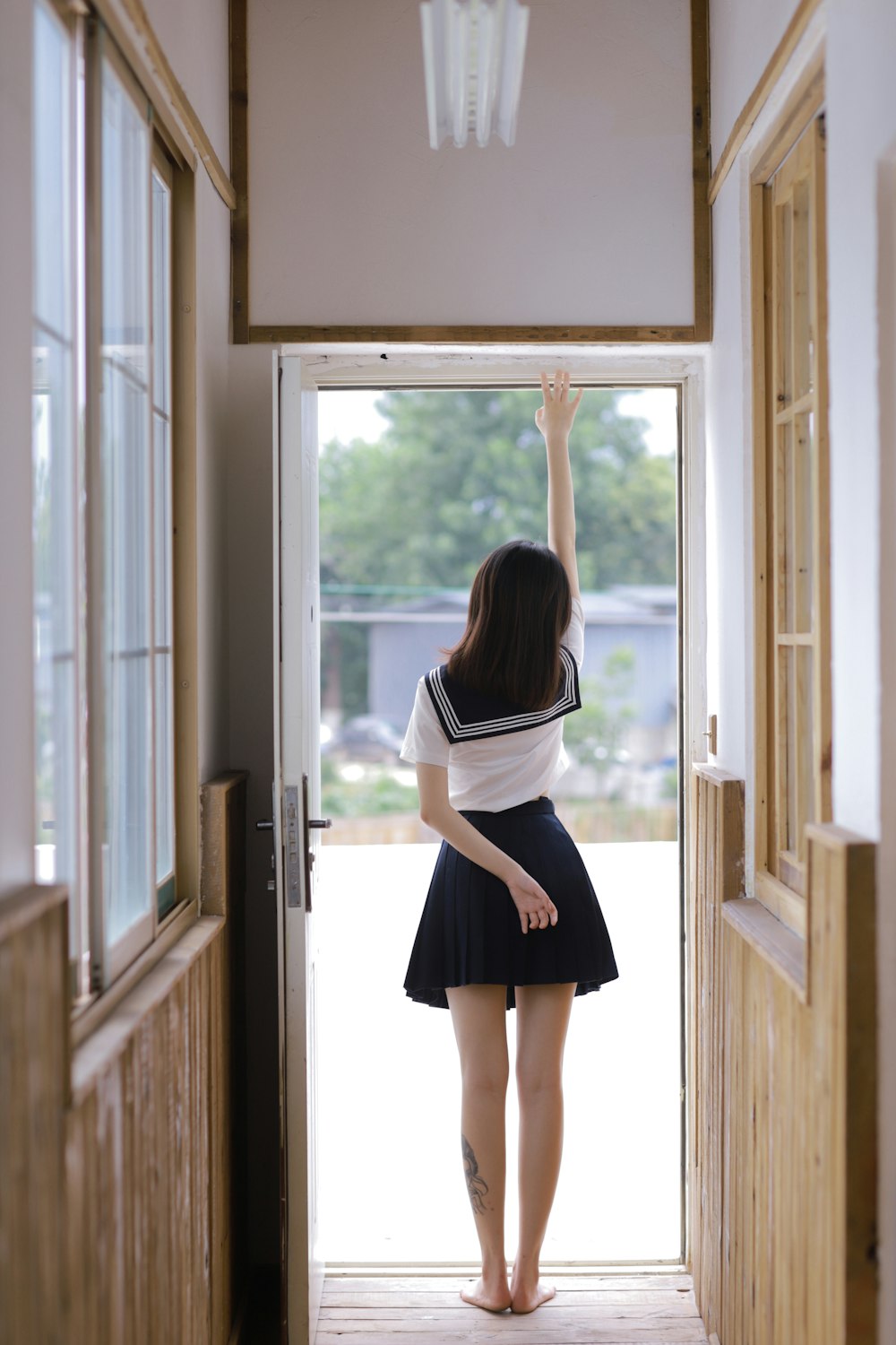 woman in white shirt and black skirt standing by the window