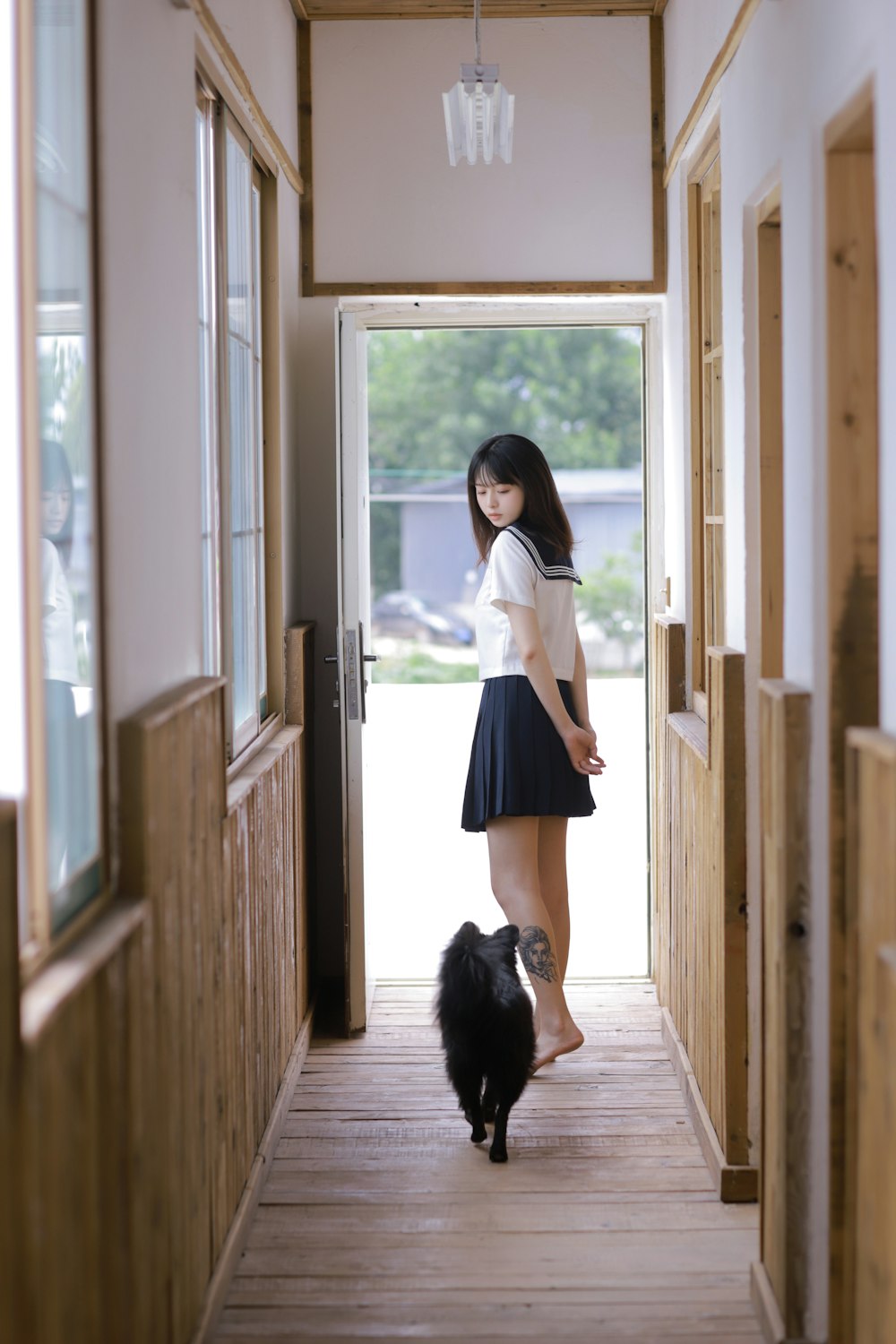 woman in white long sleeve shirt and black skirt standing beside glass window