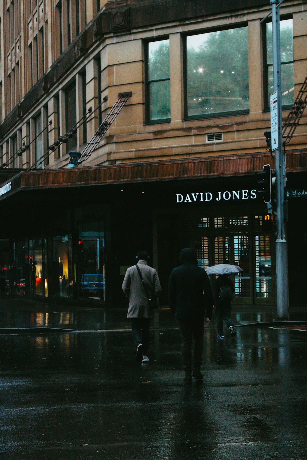 man in gray coat walking on sidewalk during night time