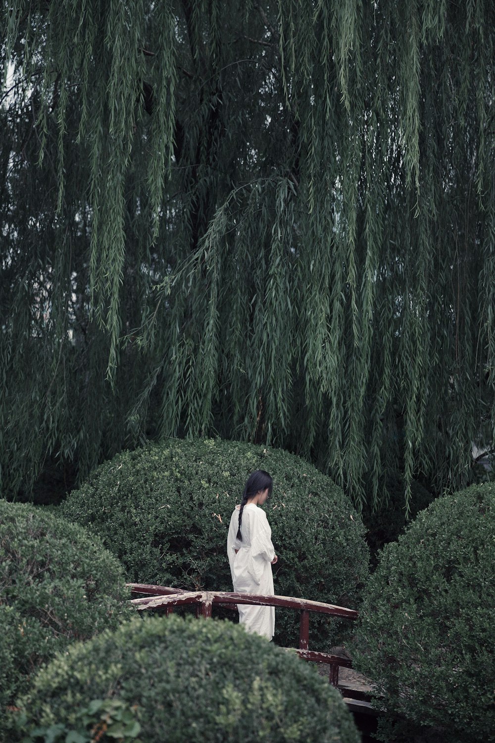 woman in white shirt and red pants standing on green grass during daytime