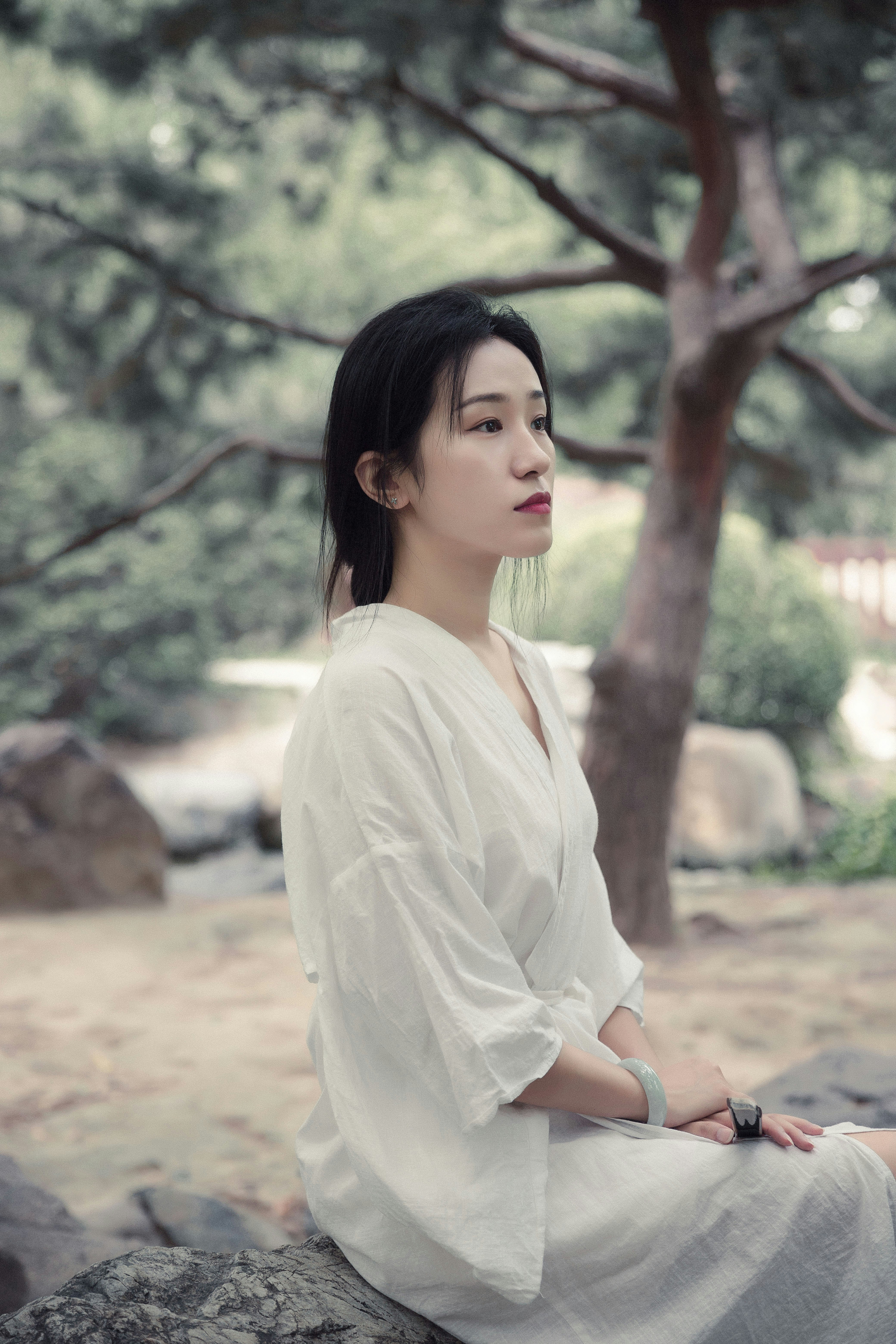woman in white long sleeve shirt standing near brown tree during daytime
