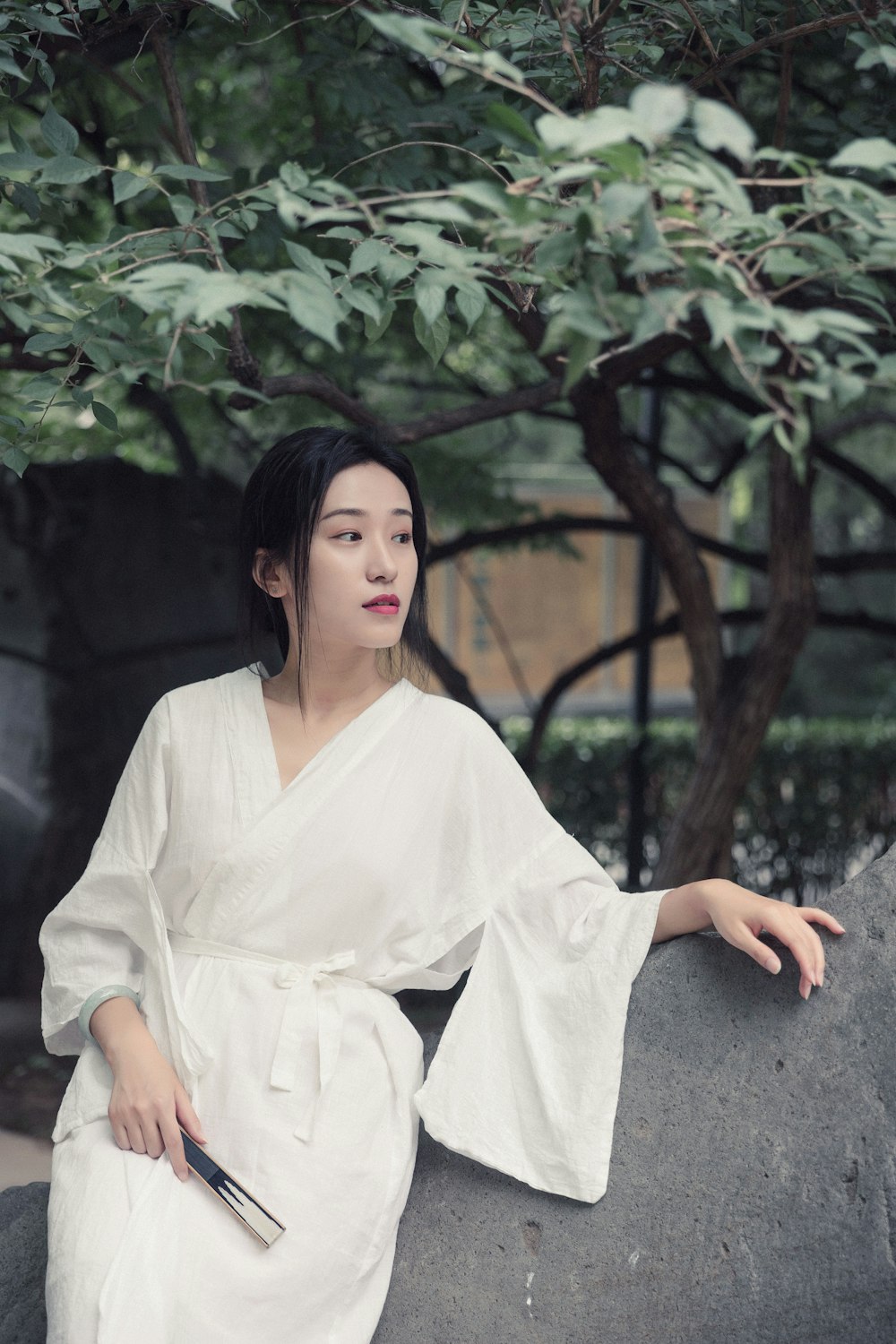 woman in white robe sitting on gray concrete floor