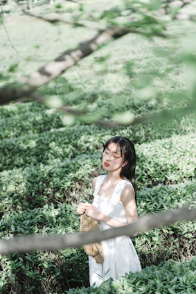 A serene woman meditating outdoors at sunrise, surrounded by soft natural light and gentle greenery.