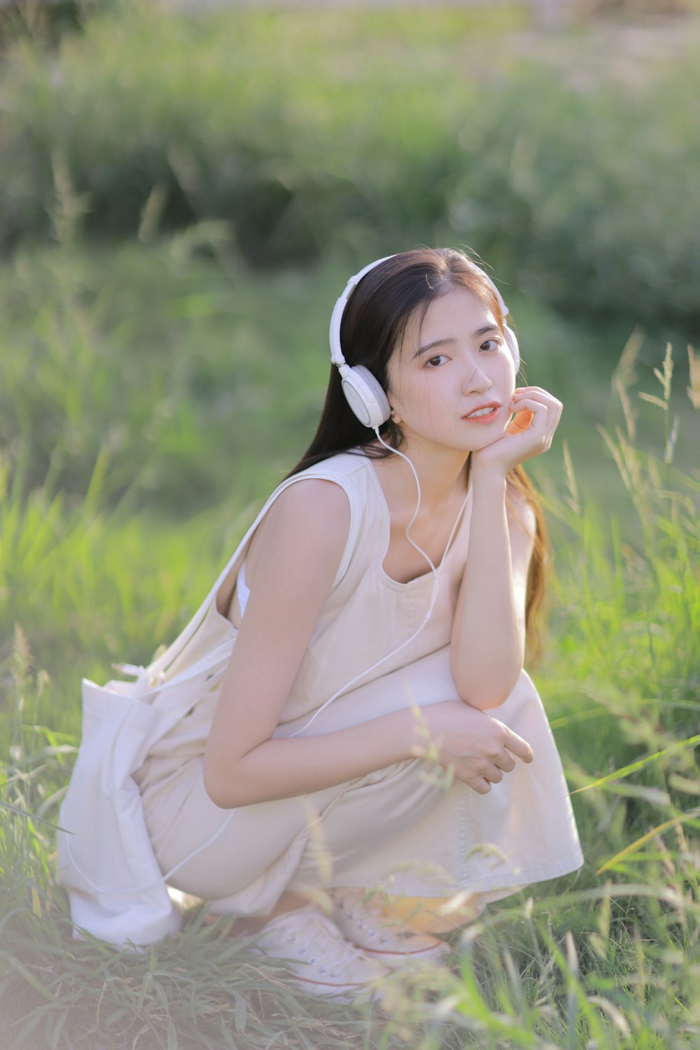 woman in white sleeveless dress sitting on green grass during daytime