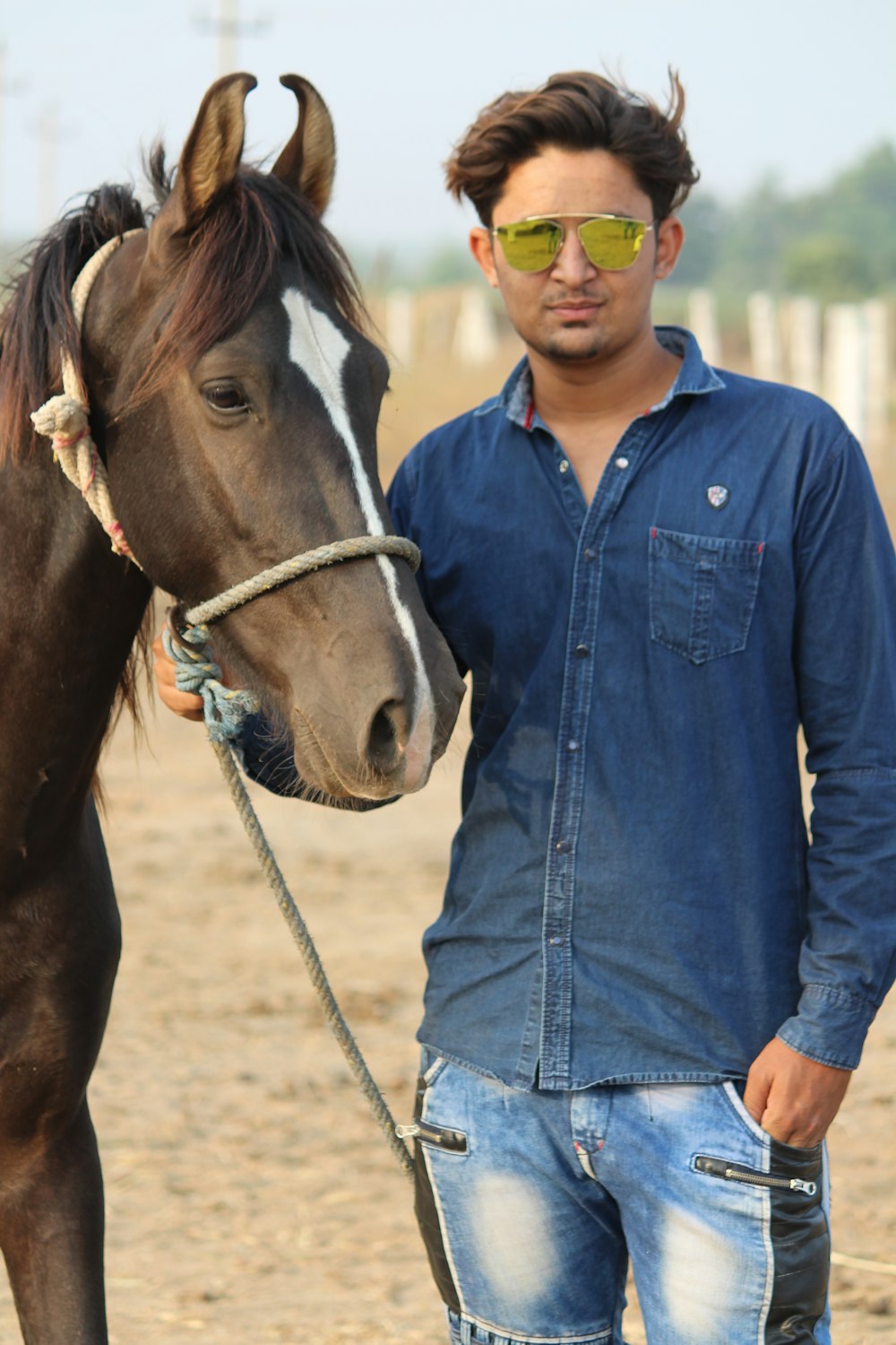 woman in blue denim button up jacket standing beside brown horse during daytime