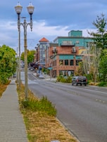 Street view of a tree-lined avenue with contemporary buildings and sidewalks.