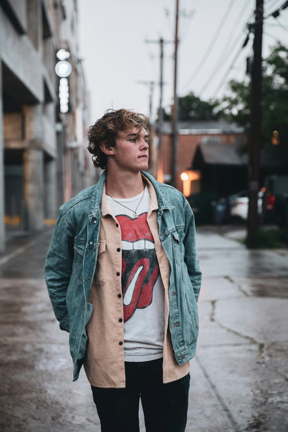 man in gray jacket standing on sidewalk during daytime